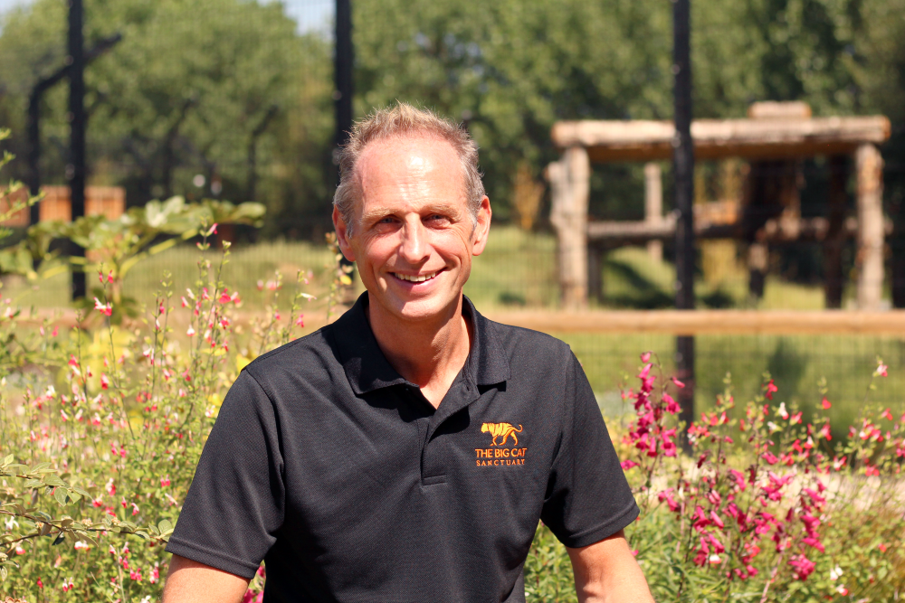 Man smiling at camera with flowers behind him