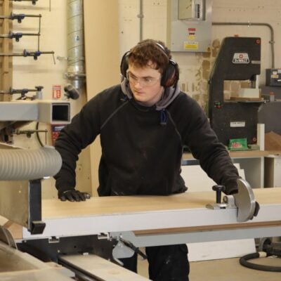 carpentry student sawing a piece of wood with a machine.