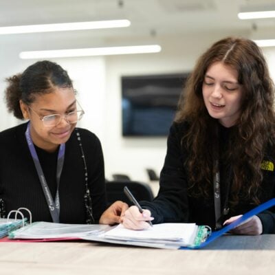 two students looking through folder of notes.