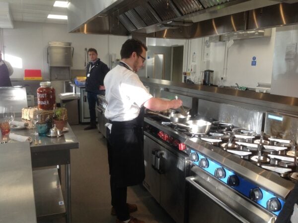 Chef using hob to cook in a big industry standard kitchen in the College.