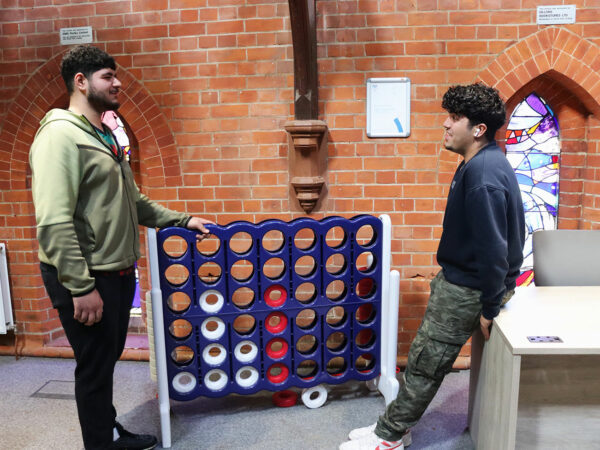 2 Students chatting in front of a giant Connect 4 game
