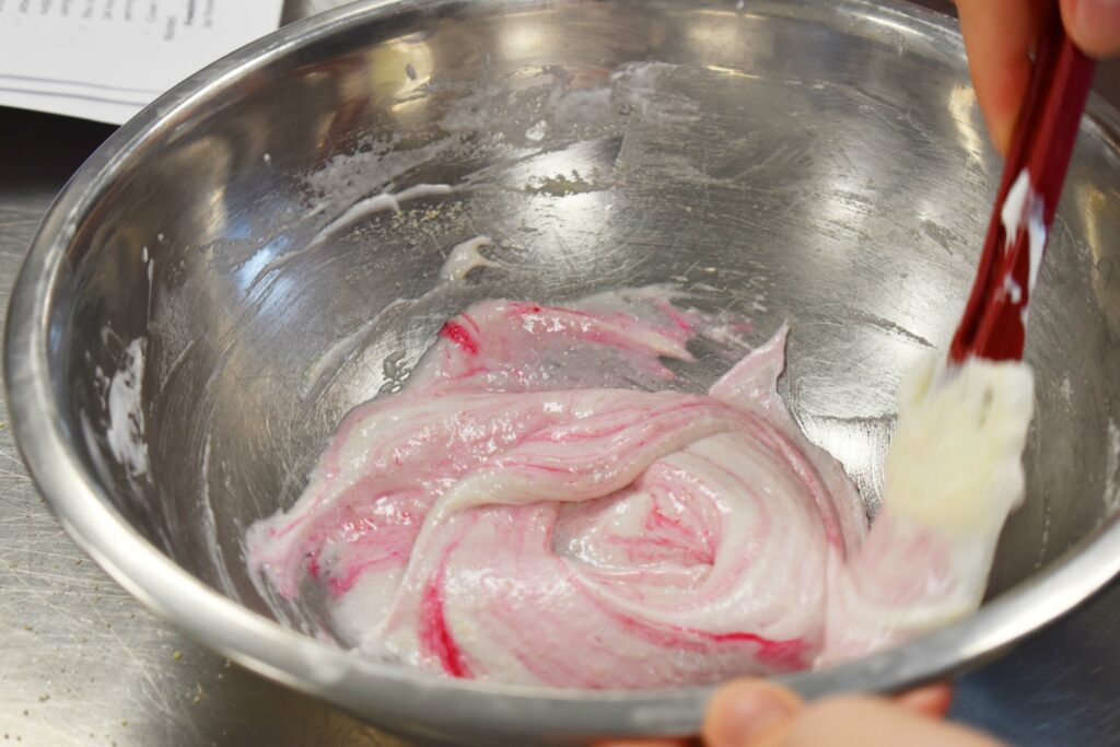 Pink swirl of food colouring in a bowl of whipped egg whites