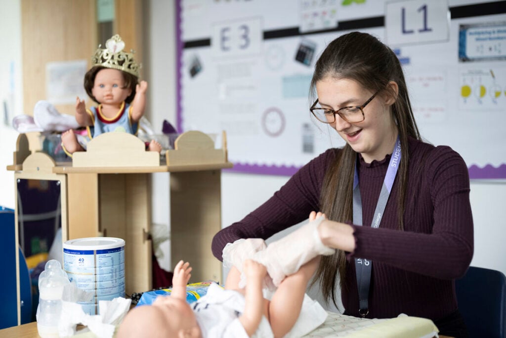 Student changing a dolls nanny
