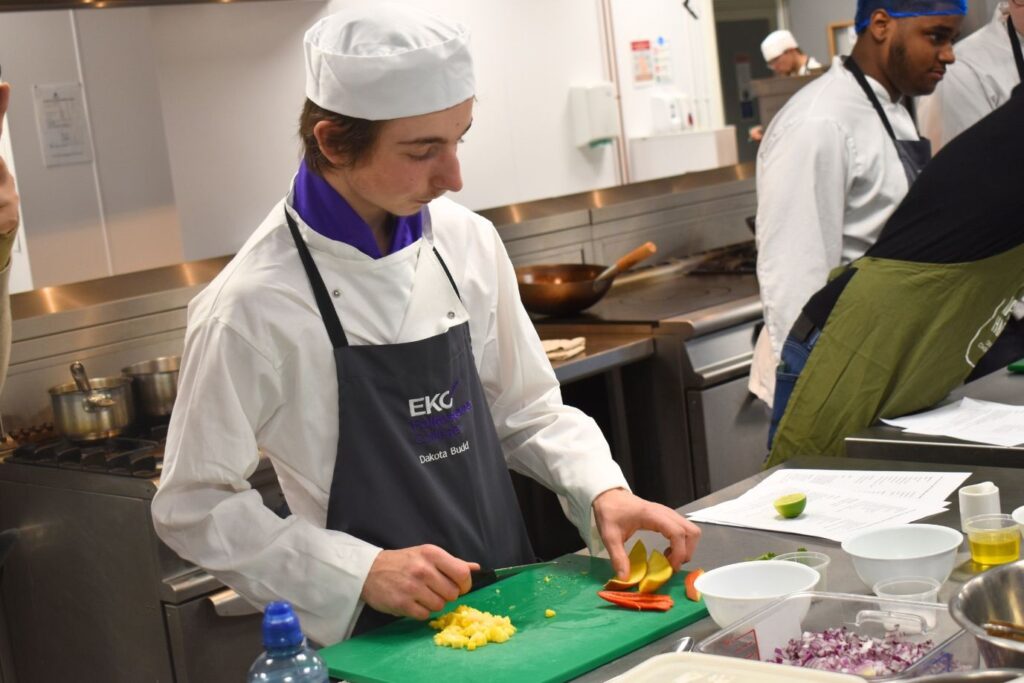 A College students chops vegetables in a student kitchen,