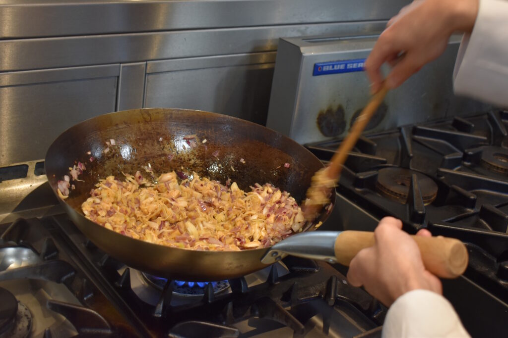 A Close up of a pan with someone cooking.