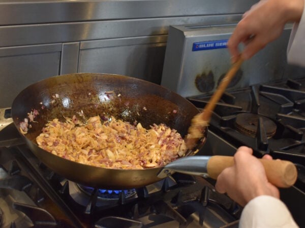 A Close up of a pan with someone cooking.