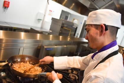 Students making a type of curry in a saucepan, stirring the ingredients.