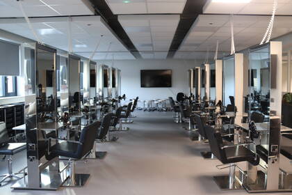 Wide view of the hair salon with all the chairs, mirrors and equipment.