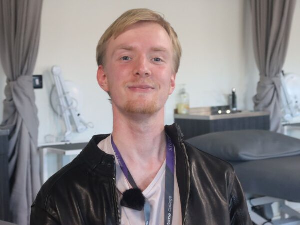Adult massage student smiling at camera, head shot.