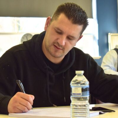 adult learning and writing at a table in the classroom