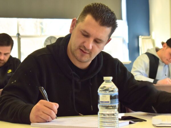 adult learning and writing at a table in the classroom