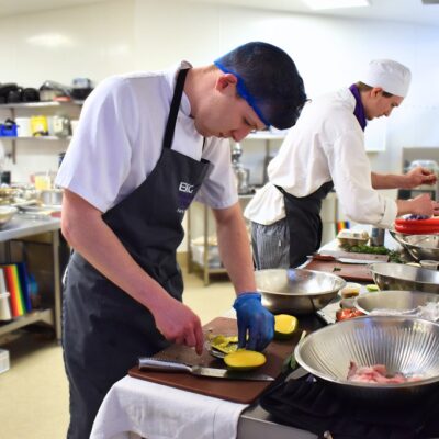 chef preparing a plate of food in a kitchen in a College environment.