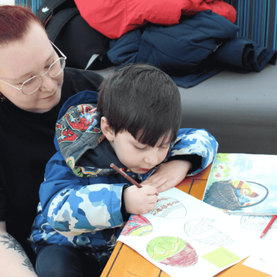 Early Years student, May, with a nursery child colouring in an Easter Egg drawing.