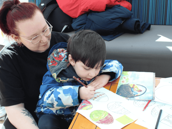 Early Years student, May, with a nursery child colouring in an Easter Egg drawing.