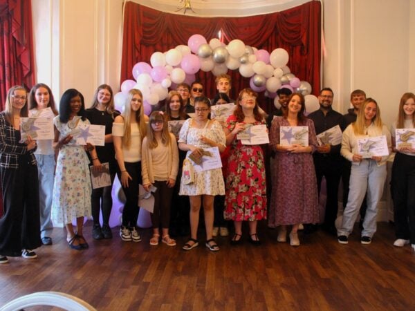 All student winners smiling under a balloon arch