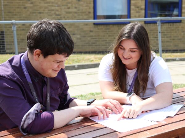 students talking together, looking at a paper