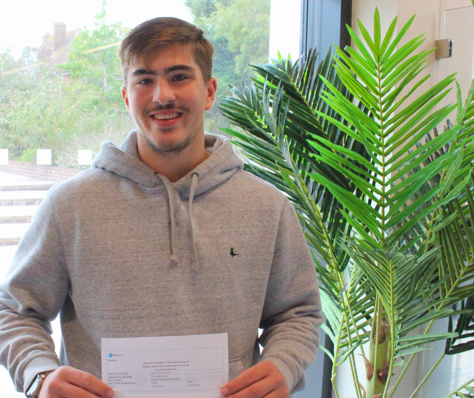 Male student smiling at the camera with his GCSE result paper.