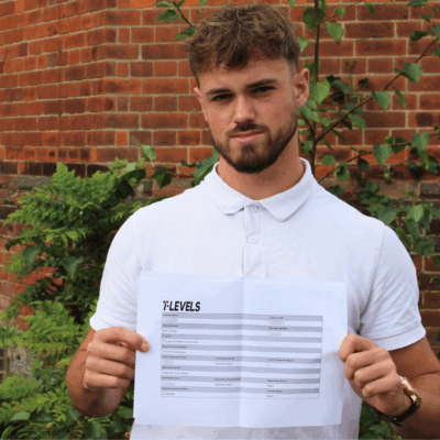 Construction student holding up his qualification and looking at the camera.