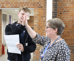 Student and lecturer giving a high five after collecting GCSE results.