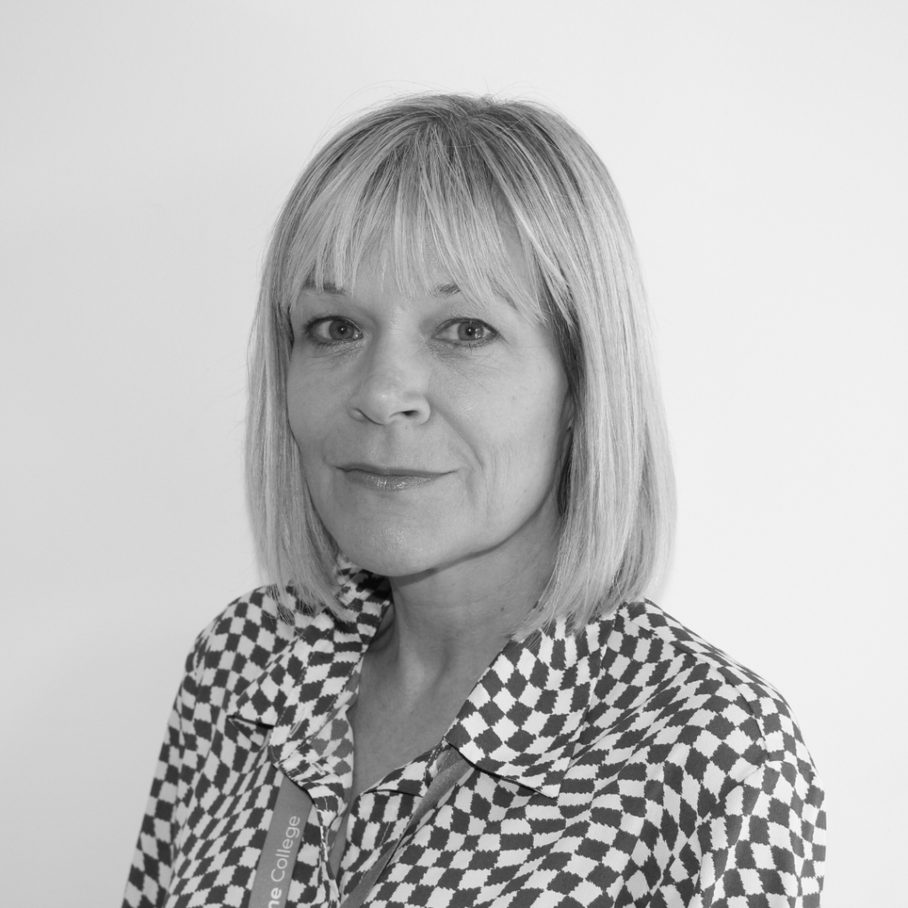 Clare smiling at camera on a plain background wearing a stripey top. The image is in black and white.