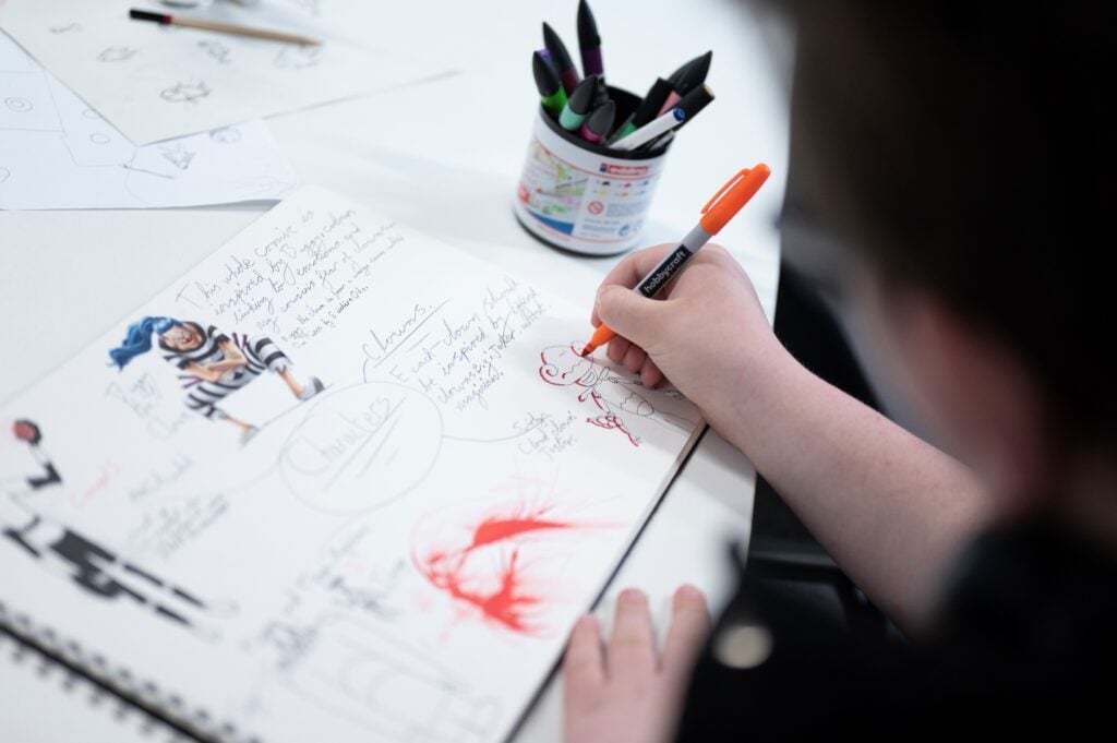 a student illustrates in a notebook