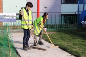 students sweeping a pathway