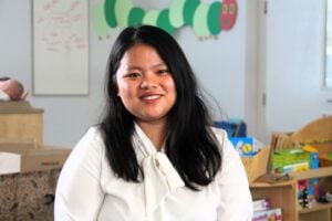 Lady sat in a early years classroom, smiling.