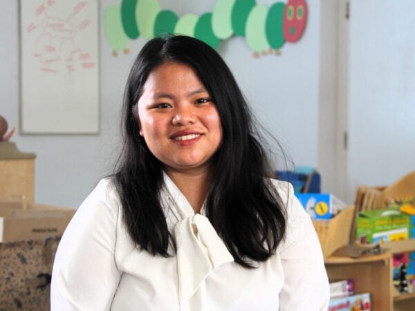 Lady sat in a early years classroom, smiling.
