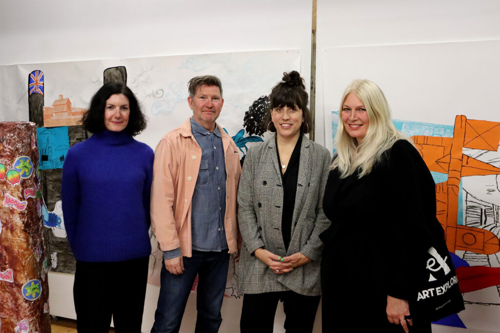 4 people stood in front of a piece of art smiling