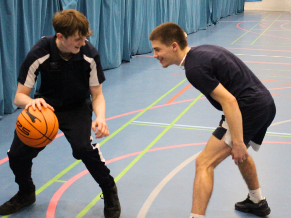 Two students playing basketball smiling