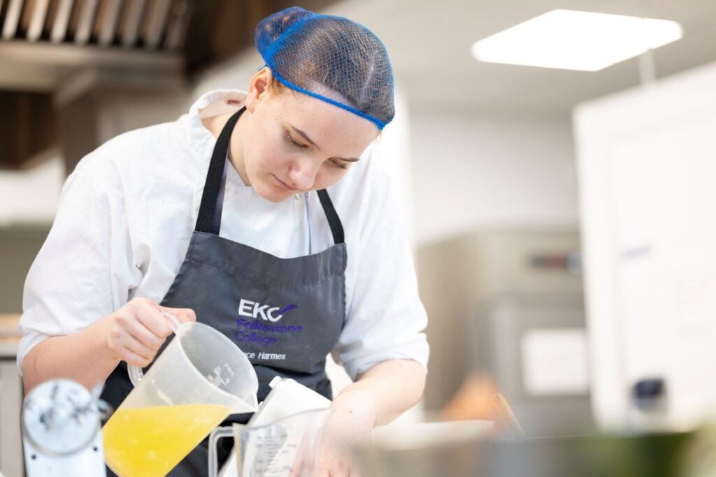 Student chef pouring stock