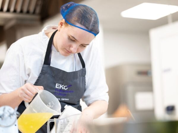 Student chef pouring stock