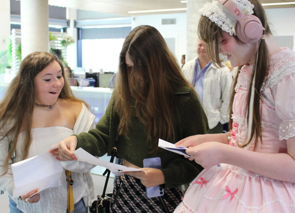 Three students opening letters together and happy surprising faces,