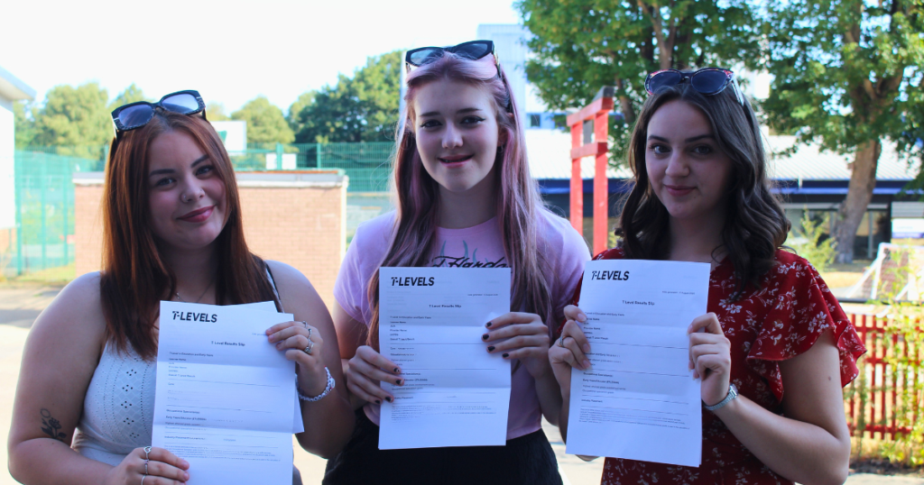Three students in a row holding up their grades. They all have long hair with sunglasses on their head. They are smiling at the camera.