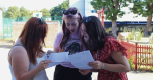 Three students excited about opening their results, looking at each others grades in shock and excitement.