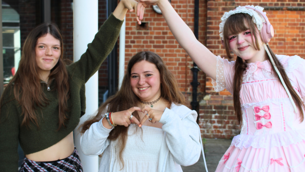 three students making a love heart with their hands.