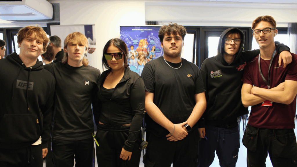 Six students in a line, all wearing black clothes looking at the camera, there are five boys and one girl.